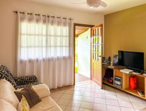 a living room with a couch and a television at Casa com piscina em Riviera de Sao Lourenco SP in Riviera de São Lourenço