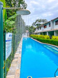 a swimming pool next to a fence with a water fountain at Casa com piscina em Riviera de Sao Lourenco SP in Riviera de São Lourenço