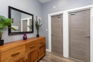 a bathroom with a dresser with a mirror and two doors at Harewood Lodge Darlington Luxury Apartments in Darlington