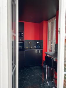 a kitchen with red walls and a black counter at Le souffle de l’amour in Melun