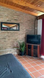 um quarto com uma televisão e uma parede de tijolos em Aires Verdes em Río Ceballos