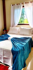 una camera da letto con un letto con lenzuola blu e una finestra di Um Lugar Agradável Em Meio a Natureza a Parati