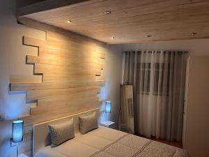 a bedroom with a wooden accent wall and a bed at Cantinho da Aldeia in Tomar