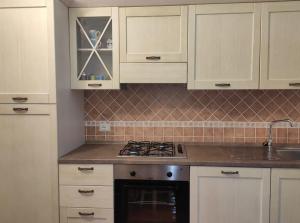 uma cozinha com armários brancos e um forno com placa de fogão em Appartamento a 50 mt dal mare em Cala Gonone