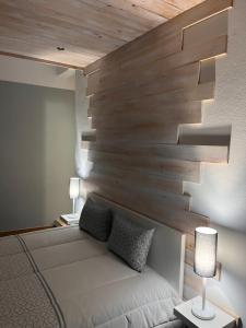 1 dormitorio con cama blanca y pared de madera en Cantinho da Aldeia en Tomar