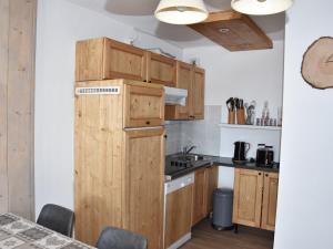 een keuken met houten kasten en een koelkast bij Appartement cosy proche commerces, animaux bienvenus, parking - FR-1-464-160 in Pralognan-la-Vanoise +11 foto's