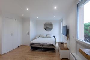 um quarto branco com uma cama e um espelho em Studio les pieds dans l'eau Argeles Sur Mer em Argelès-sur-Mer