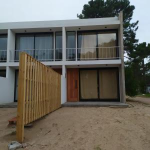 a house with a wooden gate in front of it at Duplex Pinamar norte frente al bosque in Pinamar