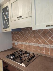 cocina con fogones y armarios blancos en Appartamento a 50 mt dal mare en Cala Gonone
