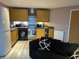 ein Wohnzimmer mit Couch und Küche in der Unterkunft MODERN 2 BEDROOM 2 BATHROOM APARTMENT SLEEPS 4 IN WARRINGTON FOR WORK AND LEISURE WITH PRIVATE PARKING BY AMAZING SPACES RELOCATIONS Ltd in Warrington
