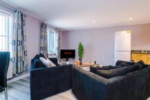 ein Wohnzimmer mit 2 Sofas und einer Küche in der Unterkunft MODERN 2 BEDROOM 2 BATHROOM APARTMENT SLEEPS 4 IN WARRINGTON FOR WORK AND LEISURE WITH PRIVATE PARKING BY AMAZING SPACES RELOCATIONS Ltd in Warrington