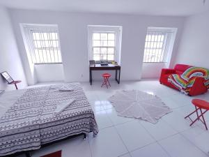 a white room with a bed and a red couch at São Francisco Aparts in Salvador