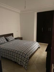 1 dormitorio con 1 cama con manta a cuadros en Magnifique Appartement Inès complexe Aida village, en Tánger