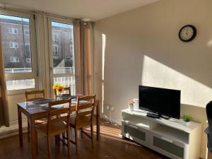 a living room with a dining room table and a television at 2-bedroom Flat in Regents Park-Euston-Camden in London