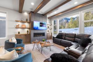 sala de estar con sofá de cuero y TV en Falling Star Ski House, en Fernie