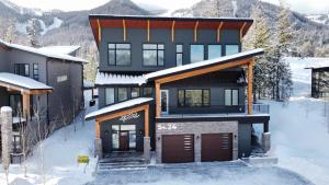 une maison dans la neige avec des montagnes en arrière-plan dans l'établissement Falling Star Ski House, à Fernie