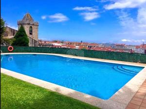 a blue swimming pool in a yard with a building in the background at Estudio impresionantes vistas con terraza y piscina in Baiona