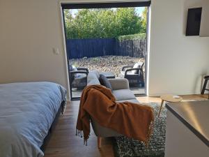 a bedroom with a bed and a chair and a sliding glass door at Studio 4 - NEW & Central in Hanmer Springs