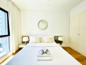 een witte slaapkamer met een groot wit bed met 2 kussens bij Airport Expo Apartment in Lissabon
