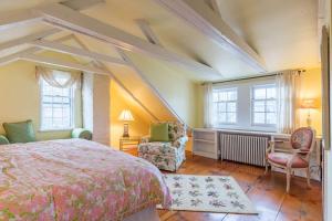 een slaapkamer met een bed, een stoel en ramen bij Rockmere Inn in Marblehead