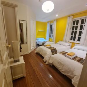 three beds in a room with yellow walls and wooden floors at Hotel Cayman in Quito