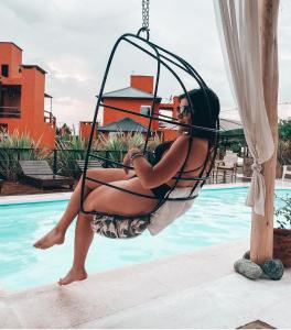una mujer sentada en un columpio junto a una piscina en Punta Piedra cabañas & suites en Los Reartes