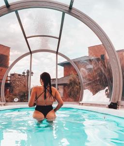 una mujer sentada en el agua en una piscina en Punta Piedra cabañas & suites en Los Reartes
