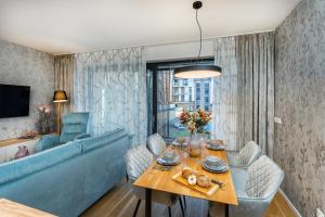 een woonkamer met een tafel en een blauwe bank bij Apartament A121 Molo Lipno s infrasaunou - Residence Koubek in Lipno nad Vltavou