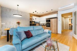 salon z niebieską kanapą i kuchnią w obiekcie Apartament A121 Molo Lipno s infrasaunou - Residence Koubek w mieście Lipno nad Vltavou
