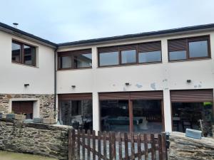 un edificio blanco con ventanas y una valla de madera en A casa do Val, en Lugo