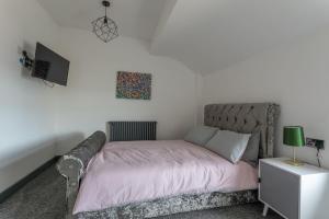 a bedroom with a bed with pink sheets and a tv at RESIDENCY LUXURY SEAFRONT HOTEL in Blackpool