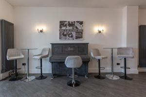 a room with a piano and four chairs and tables at RESIDENCY LUXURY SEAFRONT HOTEL in Blackpool