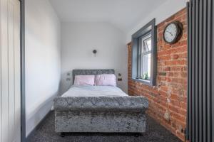 a bedroom with a bed and a brick wall with a clock at RESIDENCY LUXURY SEAFRONT HOTEL in Blackpool