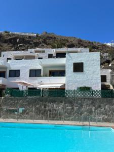 uma casa com piscina em frente a um edifício em Lovely apartment 2 rooms with big terrace in Puerto Rico em Puerto Rico de Gran Canaria