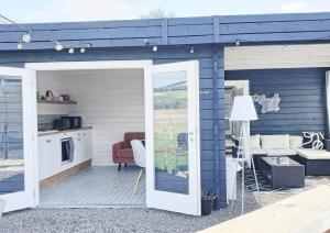 a blue house with a patio with a living room at The Wee Stay - Rural Guest Suite with Woodfired Hot Tub and outside Kitchen and covered Livingroom area in Crook of Devon