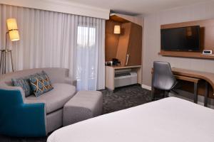 a hotel room with a couch chair and a television at Courtyard Palm Desert in Palm Desert