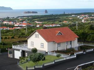 una casa bianca con tetto arancione e l'oceano di Moradia Familiar NovaVista - T3 a Madalena