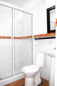 a white bathroom with a toilet and a sink at Chrisban Hotel Boutique in Buga