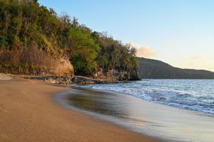 a beach with the ocean and a cliff at La Vue in Anse La Raye