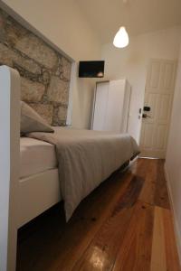 a bedroom with a bed and a stone wall at Rustic Silent Ensuites - Shared Kitchen - Self check in in Porto