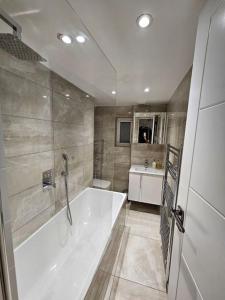 ein großes Bad mit einer Badewanne und einem Waschbecken in der Unterkunft cosy apartment Alexandra palace Haringey, London in London