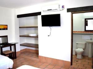 a bedroom with a bed and a tv and a toilet at Chrisban Hotel Boutique in Buga