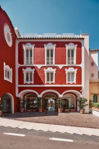 a red building with white windows and potted plants at Le Sirenuse in Positano
