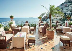 um restaurante com mesas e cadeiras e o oceano em Le Sirenuse em Positano