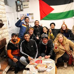 a group of people sitting around a table with a flag at Friends Hostel.Area B in Hebron