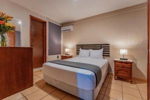 1 dormitorio con 1 cama grande y 2 mesitas de noche en Hotel Brisas 5a AV, Playa del Carmen, en Playa del Carmen