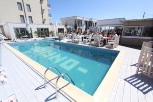 a swimming pool with people sitting at tables in a building at Oneiro Resort in Mamaia Sat/Năvodari