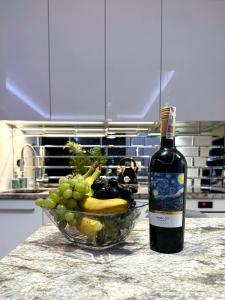 a bottle of wine and a bowl of fruit on a counter at Hanza Tower Apartament Times Square in Szczecin