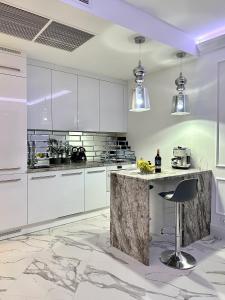 a kitchen with white cabinets and a marble counter at Hanza Tower Apartament Times Square in Szczecin