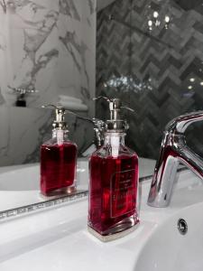 a red bottle of soap sitting on a bathroom sink at Hanza Tower Apartament Times Square in Szczecin